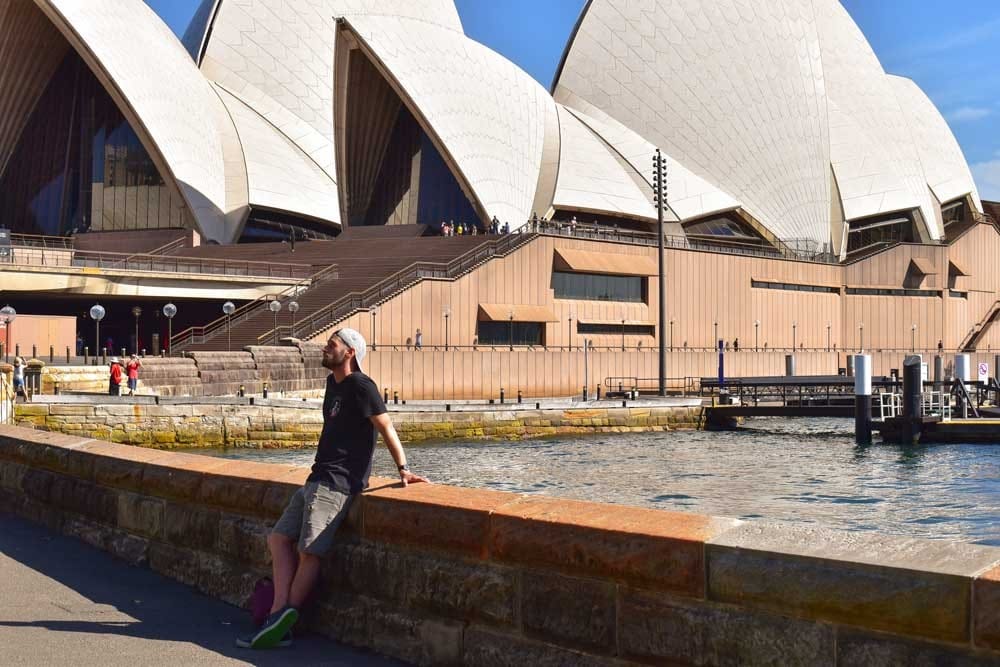 vivir en Sydney chico con una gorra posando delante de la Ópera de Sydney